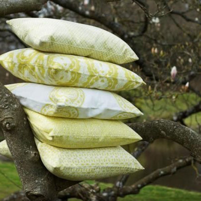 Stack of pale yellow and white soffi mandala cushion covers with delicate green floral designs on tree branches