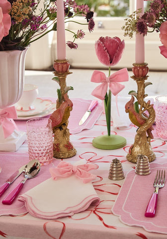 A dahlia pink petal candleholder tole with a pink tulip and bow in a green base flanked by ornate golden bird holders