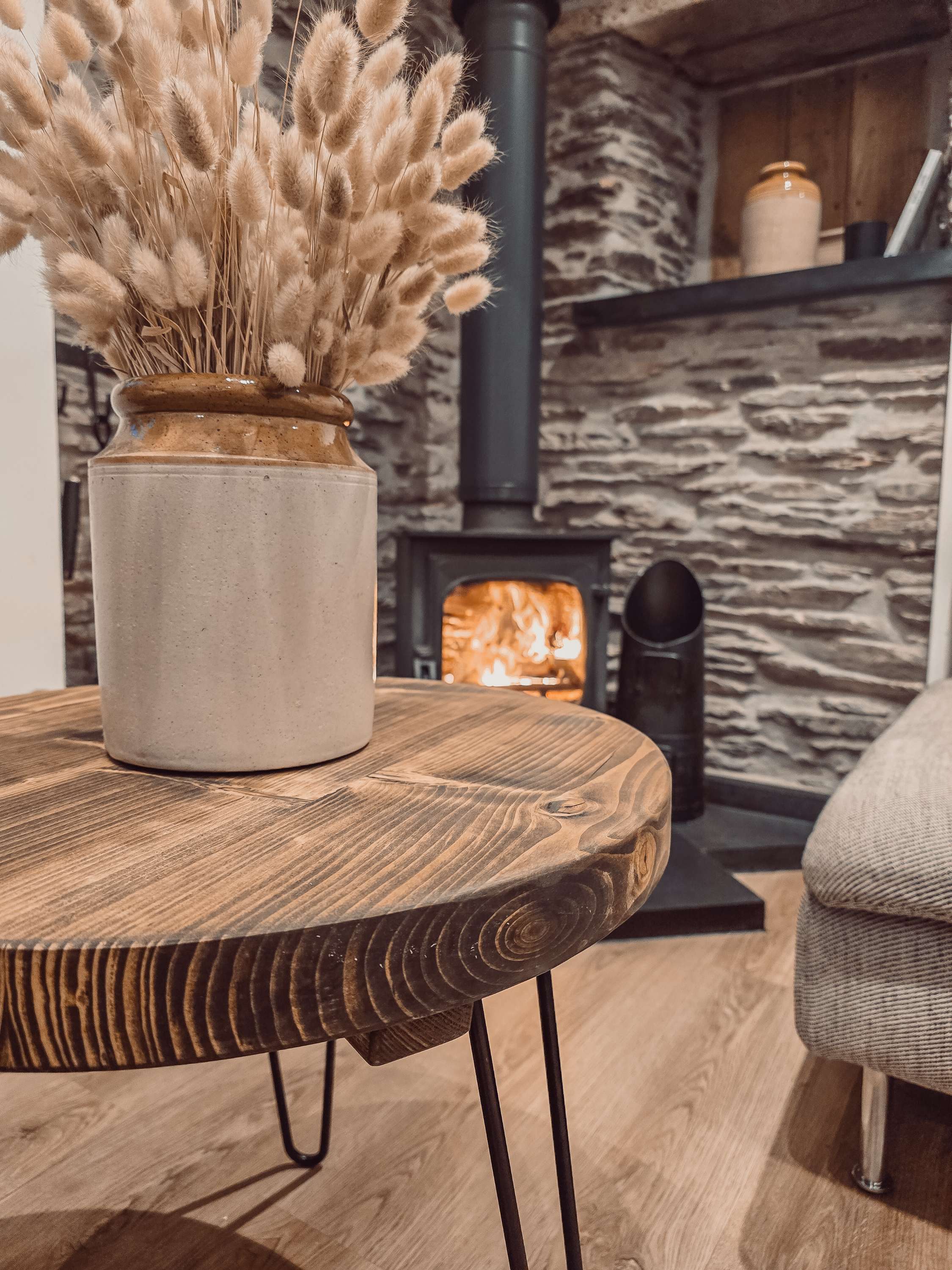 Cream-colored ceramic vase with gold-toned rim on dalva round coffee table with rustic earthy finish