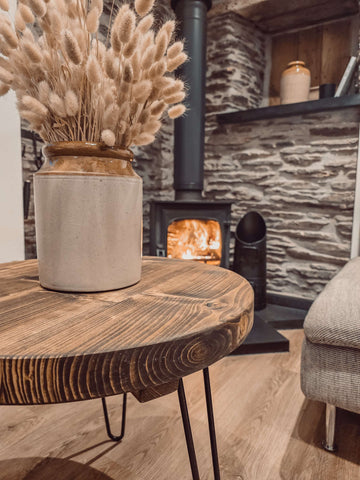 Cream-colored ceramic vase with rustic finish and gold rim on dalva walnut round coffee table for stylish decor