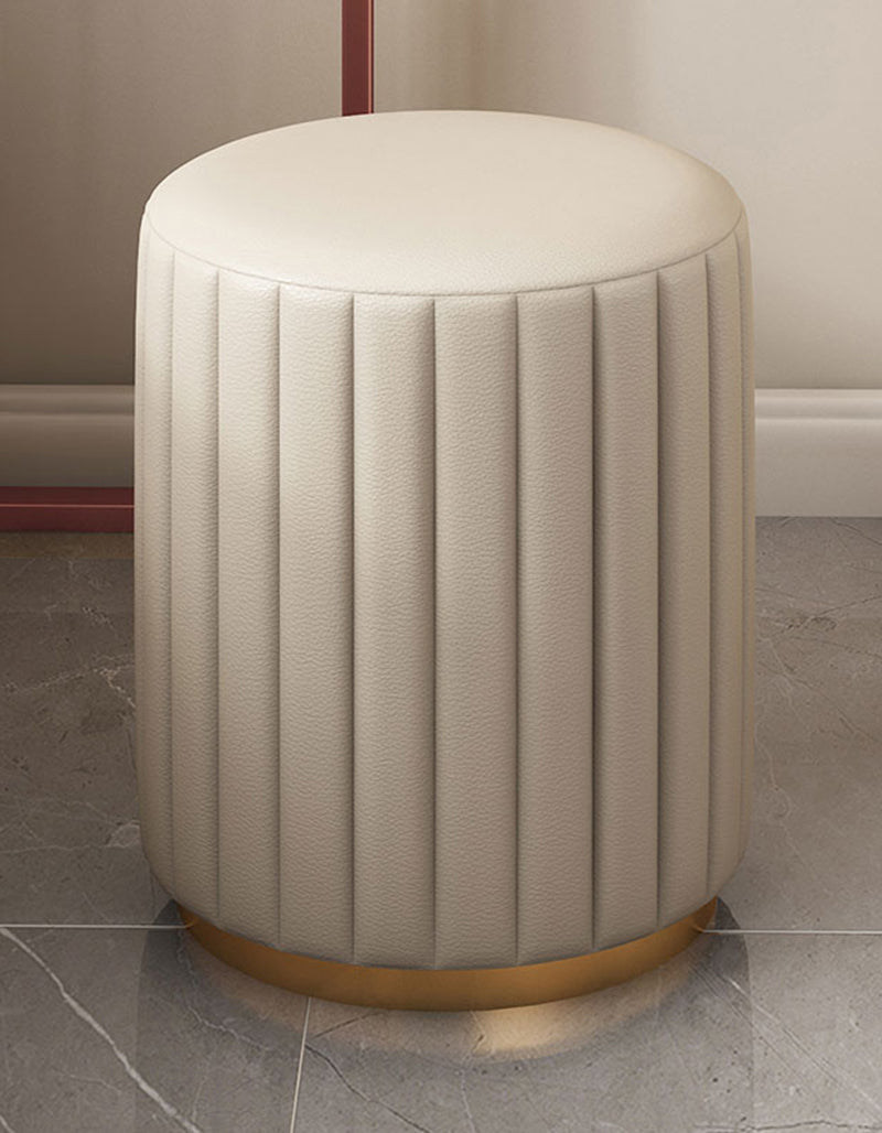 Cream-colored upholstered cylindrical stool with vertical pleats and gold base for damion dressing table setup