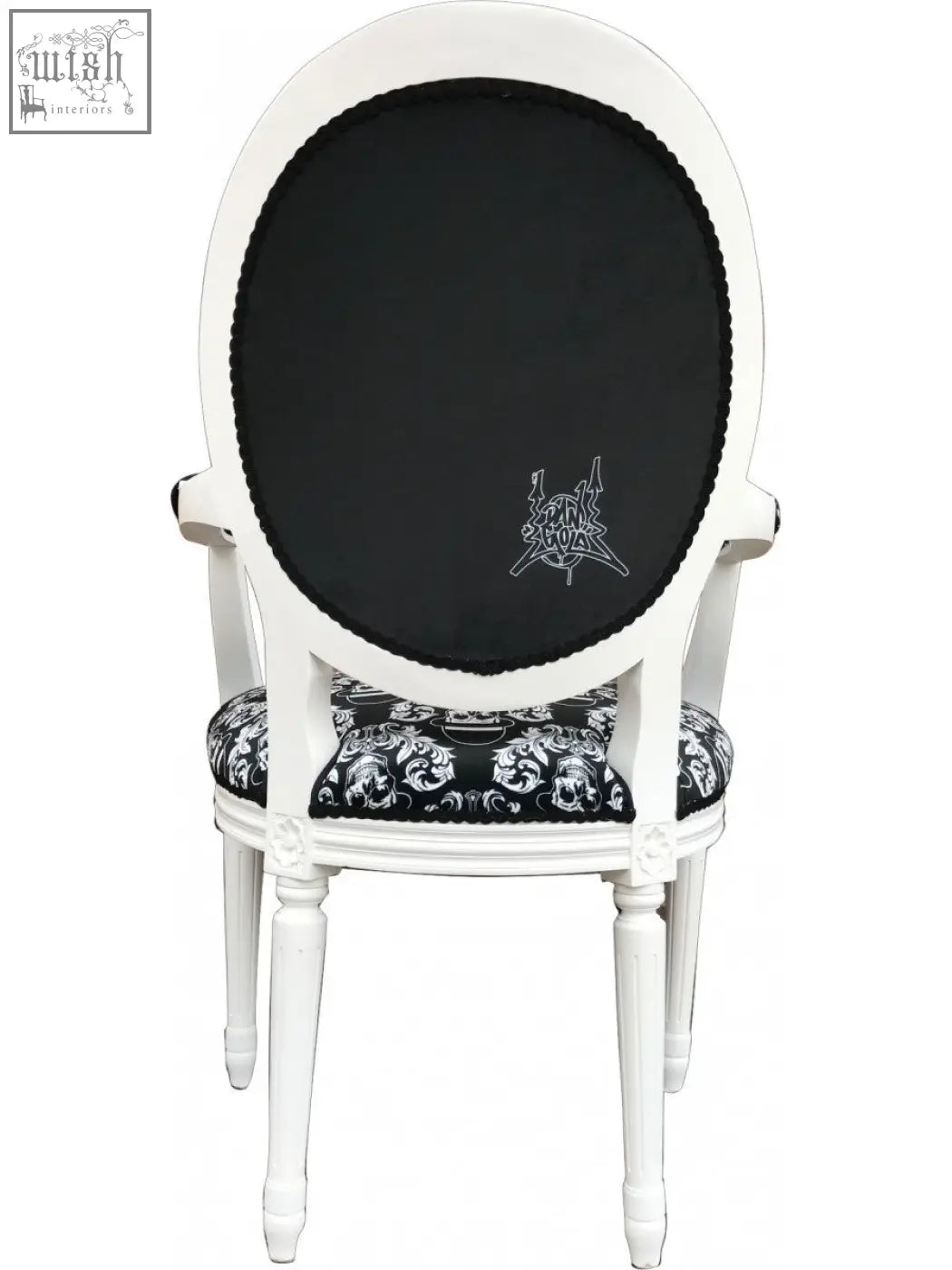White oval-back bowler arm chair by dan gold with black skull and crossbones upholstered seat and embroidered trim