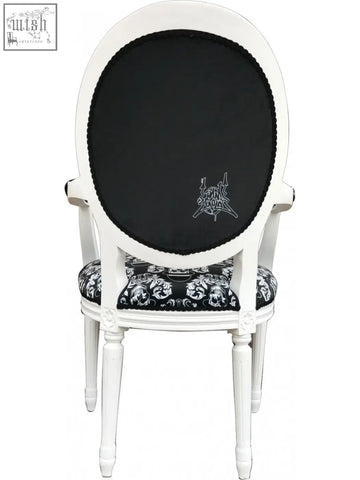 White oval-back bowler arm chair by dan gold with black skull and crossbones upholstered seat and embroidered trim
