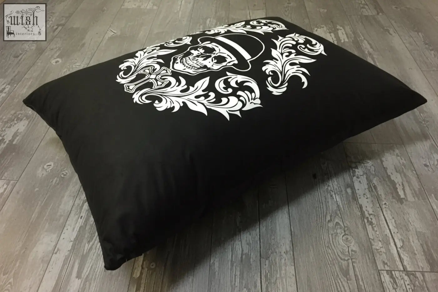 Black rectangular floor pillow with bold white skull and floral design from dan gold bowler cushion collection