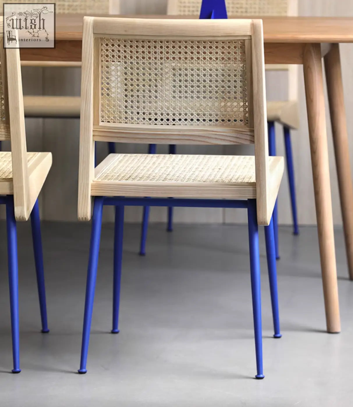 Dana rattan dining chair with light wood frame, woven cane seat and back, and vibrant blue metal legs perfect for dining rooms