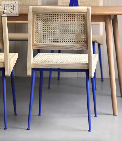 Dana rattan dining chair with light wood frame, woven cane seat and back, and vibrant blue metal legs perfect for dining rooms