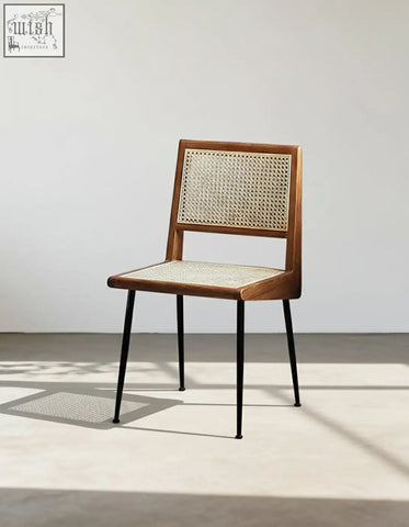 A sleek dana rattan dining chair with wooden frame, woven cane back and seat, and black metal legs perfect for dining rooms