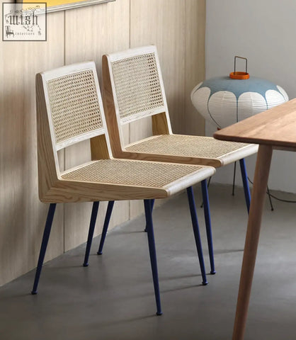 Two dana rattan dining chairs with light wood frames, woven cane seats, and navy blue metal legs
