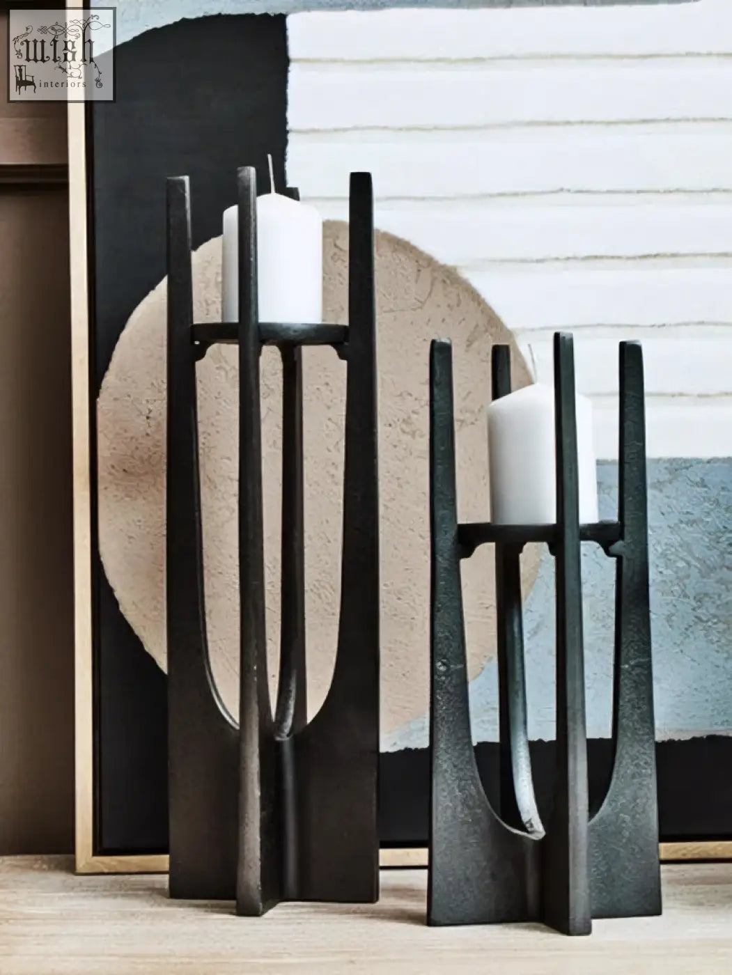 Large grey black metal candle holder with minimalist geometric design holding white pillar candles