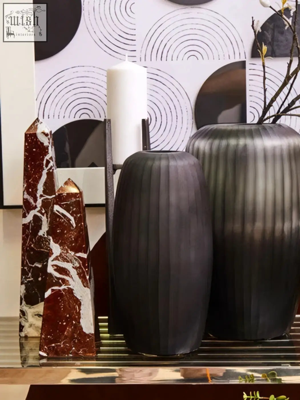 Two large grey ceramic candle holders with a matte finish and vertical ribs for pillar candles on a reflective surface