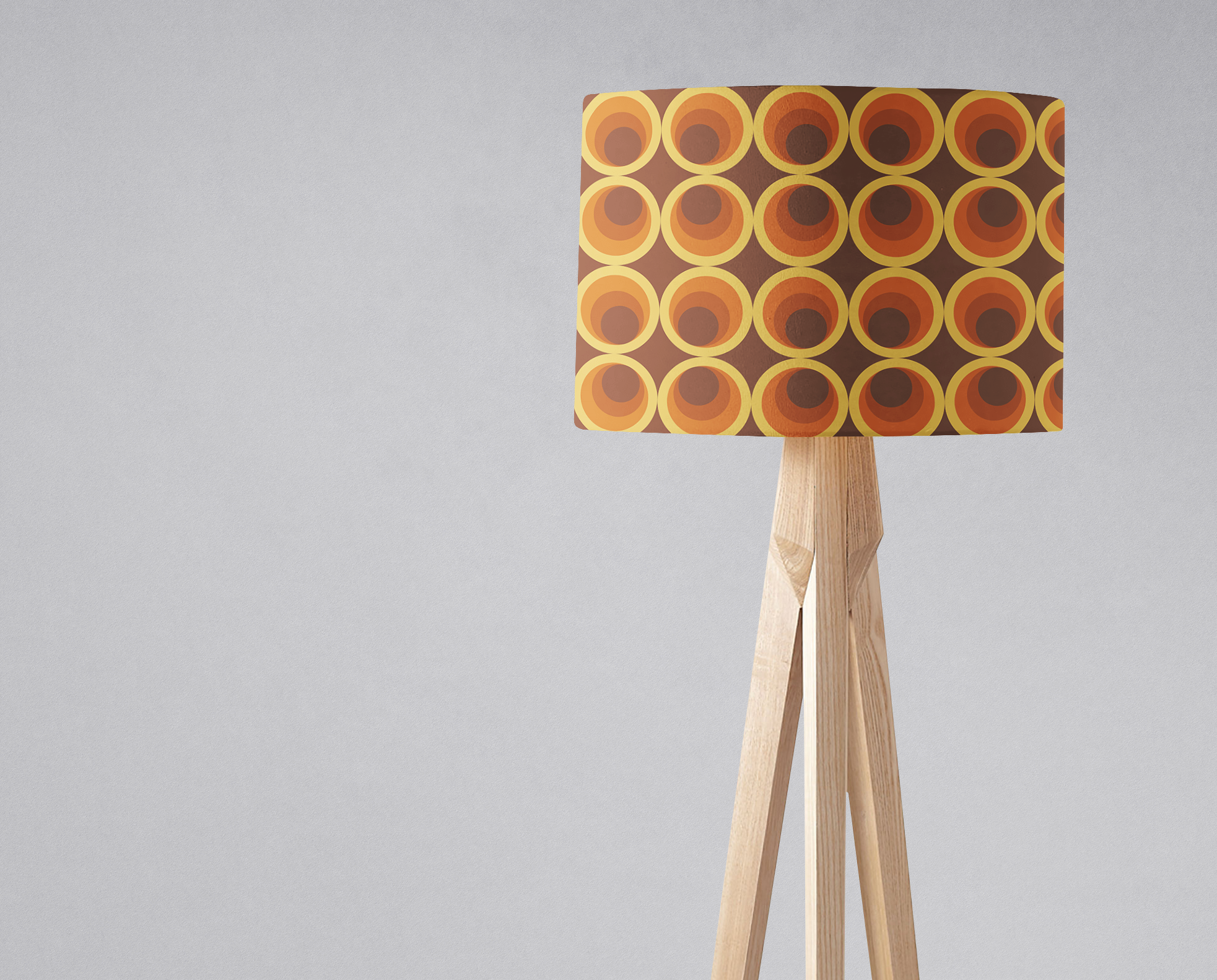 Dark brown retro 1970s table lamp with concentric orange and yellow circles on a cylindrical lamp shade and wooden legs