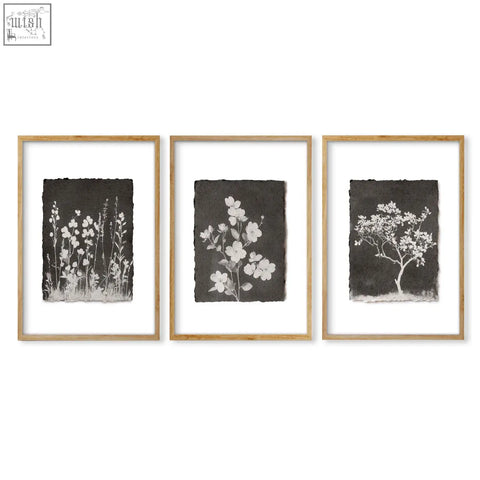 Set of three brown wall art botanical prints with white floral and tree silhouettes in light wood frames for dark brown wall