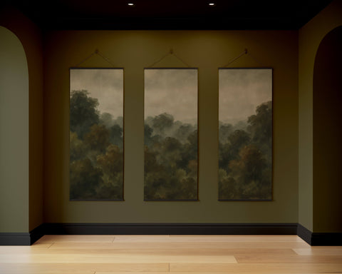 Three vertical canvas paintings of a misty dark forest tapestry hang on an olive green wall as a forest tapestry decor