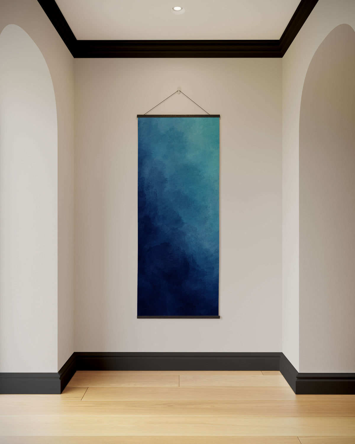 A dark ombre watercolour tapestry with a deep blue to teal gradient framed by a thin black border hanging on the wall