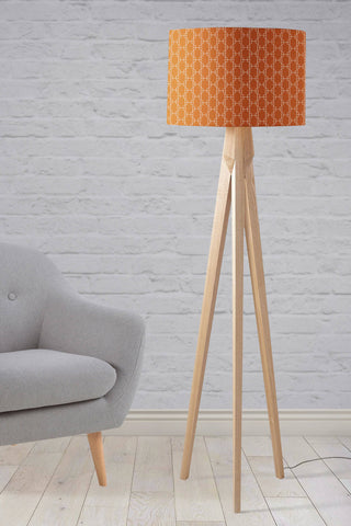 A modern tripod floor lamp with a dark orange lampshade featuring a white geometric design and wooden legs perfect as a table lamp