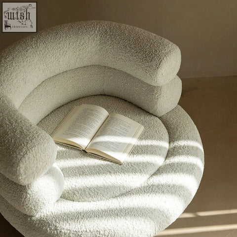 A cozy cream-colored darlene armchair made of soft boucle with a plush textured surface and curved layered design