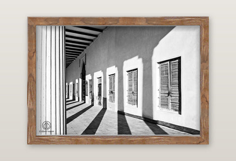 Fine art black and white photo by david ballam showing a sunlit courtyard with white walls and wooden shutters