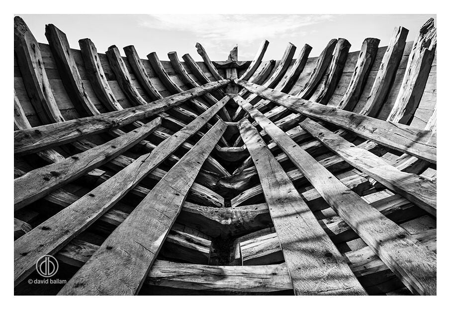 The interior framework of a wooden boat under construction with weathered planks by david ballam fine art