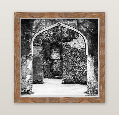 Fine art black and white photo by david ballam featuring an arched stone doorway in a rustic wooden frame