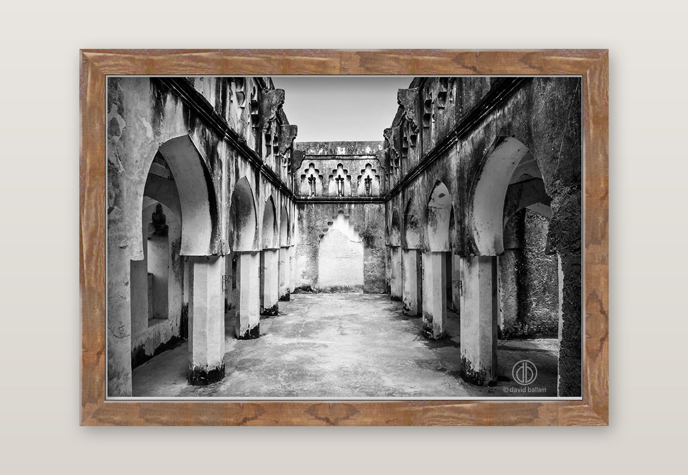 Black and white fine art photo by david ballam showing an ancient stone arcade with arched columns and weathered walls