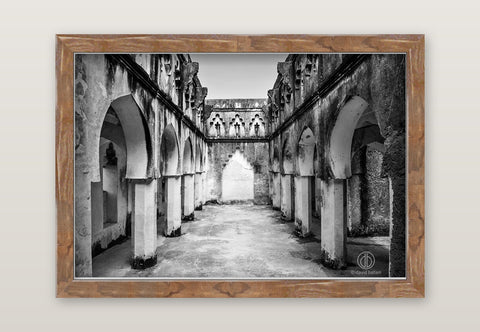 Black and white fine art photo by david ballam showing an ancient stone arcade with arched columns and weathered walls