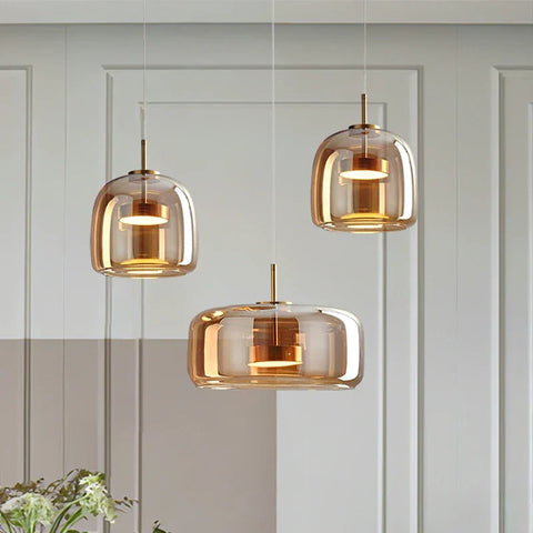 Three amber-tinted glass pendant lights with brass accents hanging from ceiling in decao light design
