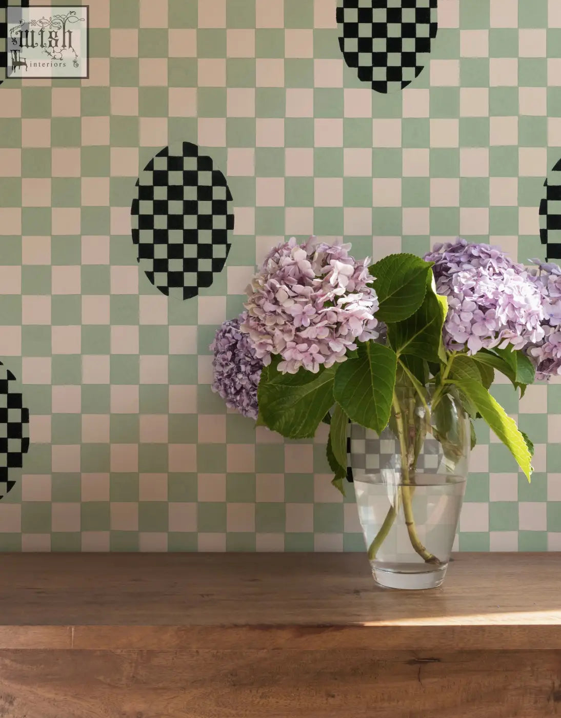 A clear glass vase with light purple hydrangeas complements micaela sharp seafoam bliss wallpaper with ethical digital printing
