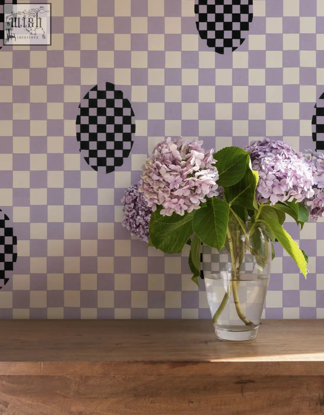 A clear glass vase with light purple hydrangeas complements micaela sharp violet veil wallpaper with digital printing