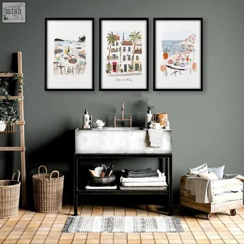 Black framed watercolor wall art prints depicting parisian scenes hang above a concrete sink in sotto il sole set