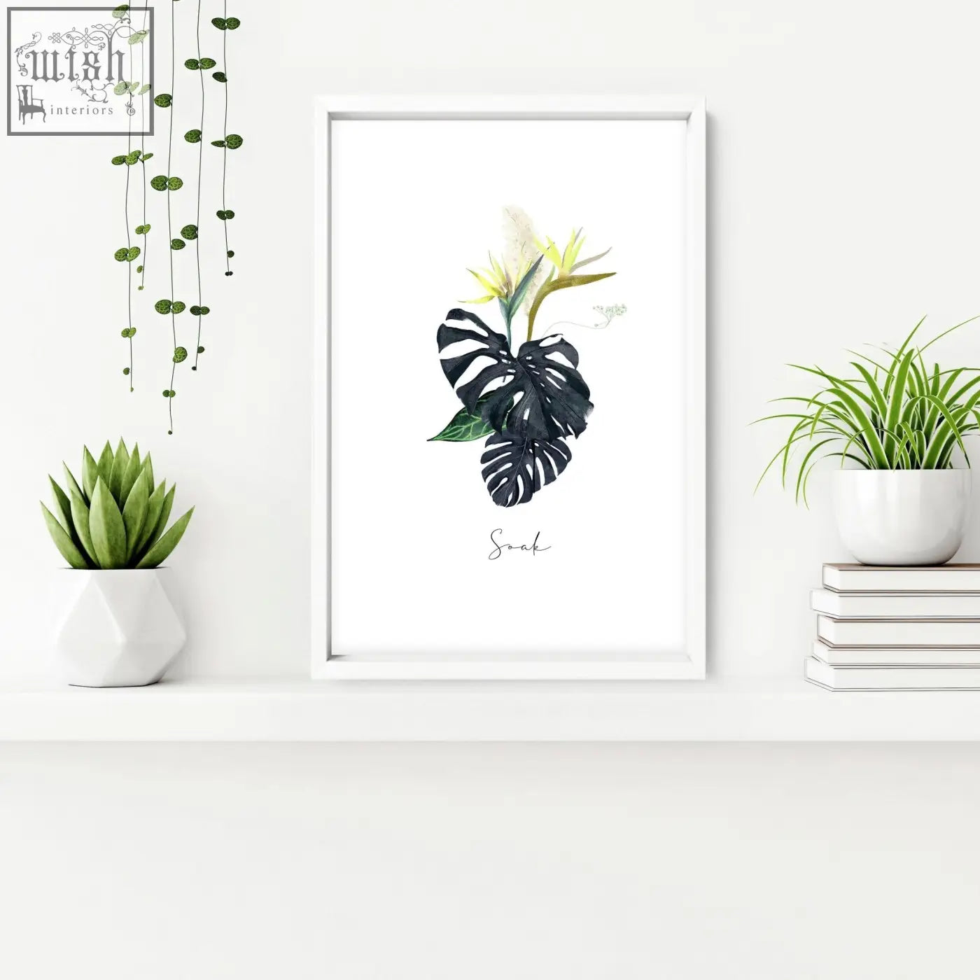 White-framed tropical wall art with black monstera leaves yellow flowers and soak text perfect for bathroom walls