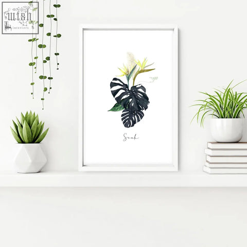 White-framed tropical wall art with black monstera leaves yellow flowers and soak text perfect for bathroom walls