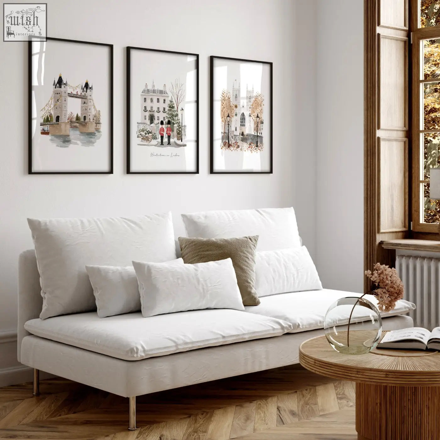White upholstered sofa with sleek metal legs and cushions beneath decorative wall hangings london bridge travel art prints