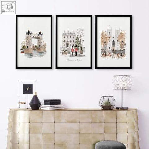 Three black-framed decorative wall hangings of london landmarks displayed above a gold-toned console table in a living room