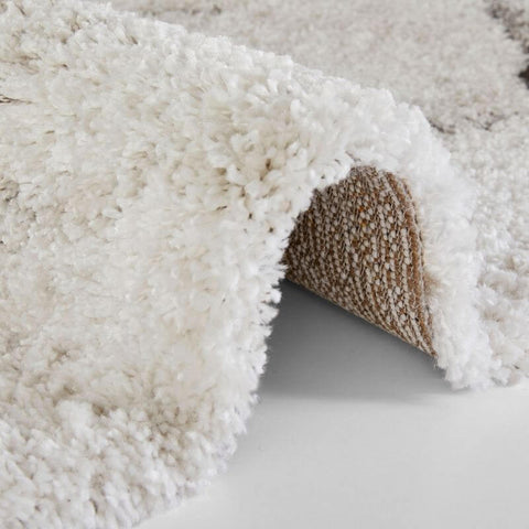 A deep-pile velour rug cream colour with a plush white shaggy textured surface and woven beige backing