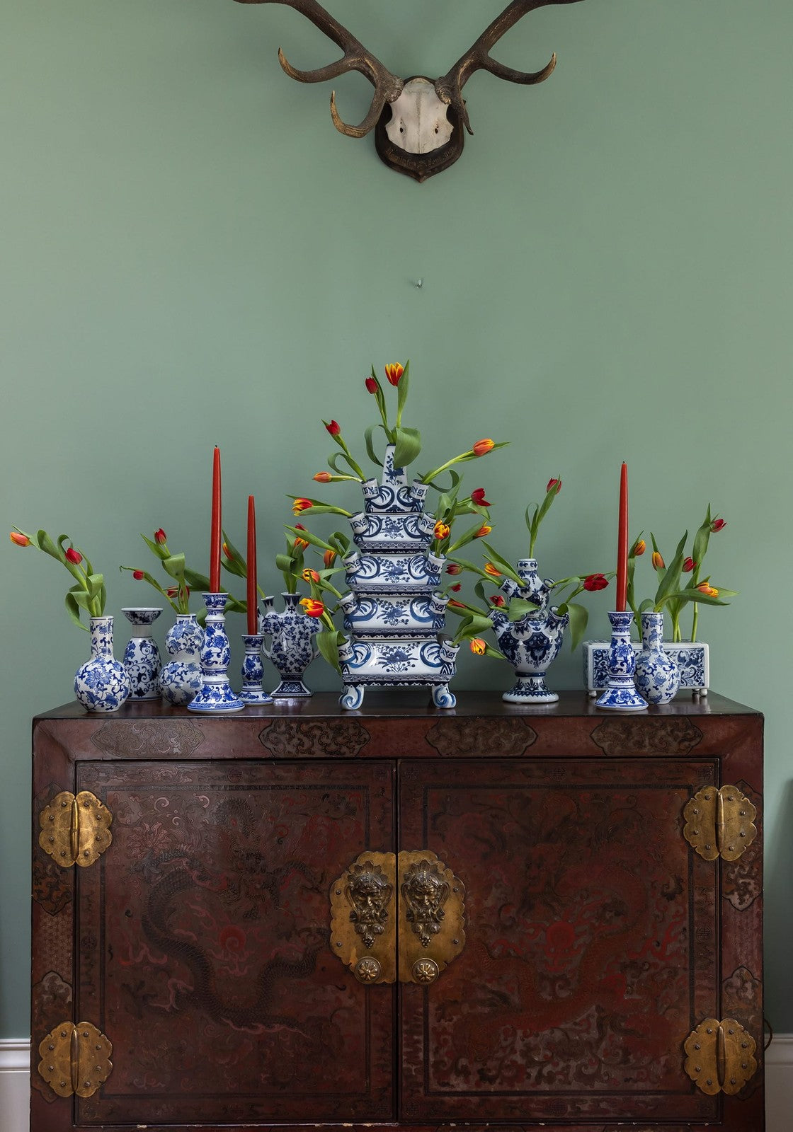 A multi-tiered blue and white porcelain delft tulipiere rectangle vase with floral patterns on a dark wooden cabinet