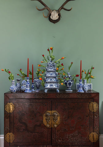 A multi-tiered blue and white porcelain delft tulipiere rectangle vase with floral patterns on a dark wooden cabinet