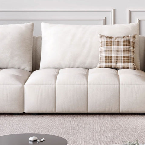 Cream-colored tufted delilah violet two seater sofa with plaid accent pillow and soft fabric upholstery