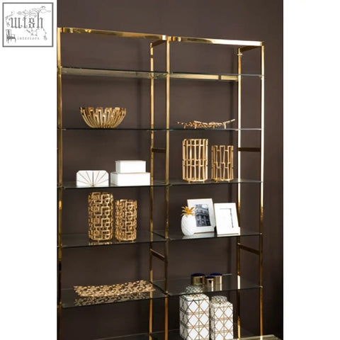Gold-toned metal bookshelf with glass shelves displaying delphi aluminium candle holders and decorative items