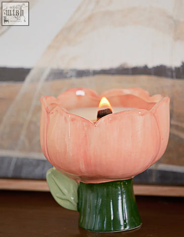 A peach ceramic tulip-shaped delphine scented candle holder with green stem and lit wax candle, ask about shipping cost or offer financing
