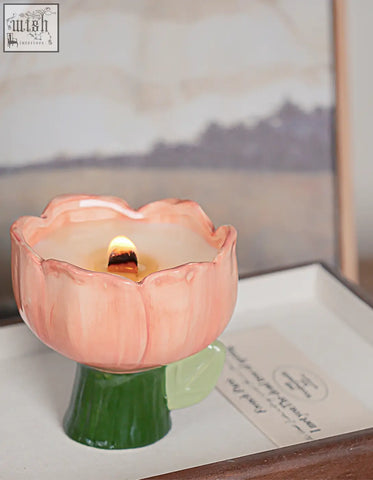 Pink ceramic flower-shaped delphine scented candle holder with lit wick and green stem base offering financing options