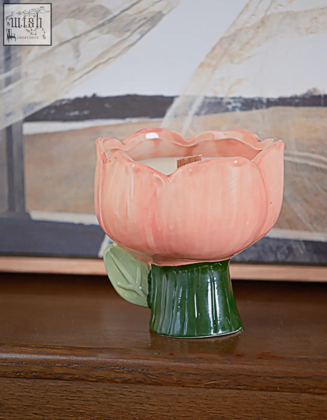A pink ceramic tulip candle with green stem and leaf base in the delphine scented collection with offer financing