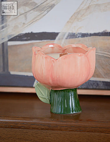 A pink ceramic tulip candle with green stem and leaf base in the delphine scented collection with offer financing