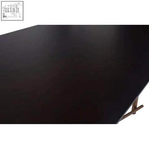 Black matte finish tabletop of delta walnut veneer dining table with sleek brass legs and minimalist design