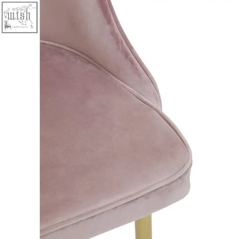 A soft blush pink velvet dining chair with sleek modern design and gold toned legs perfect as a pink velvet chair