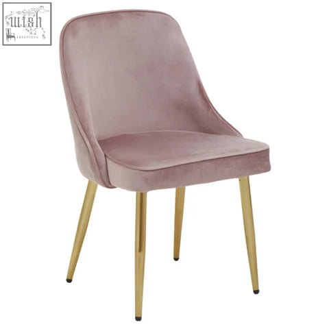 A demi dusky pink velvet dining chair with soft pink velvet upholstery and slender gold metal legs