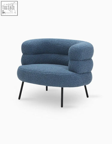 Blue plush demure boucle armchair with rounded cushioned form and black metal legs adds art deco glamour