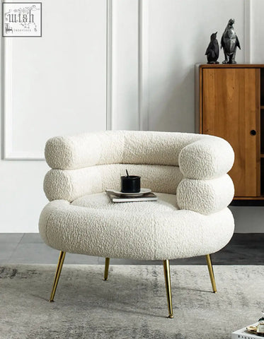 Cream-colored demure boucle armchair with plush sheepskin texture and gold-tone legs adds art-deco glamour