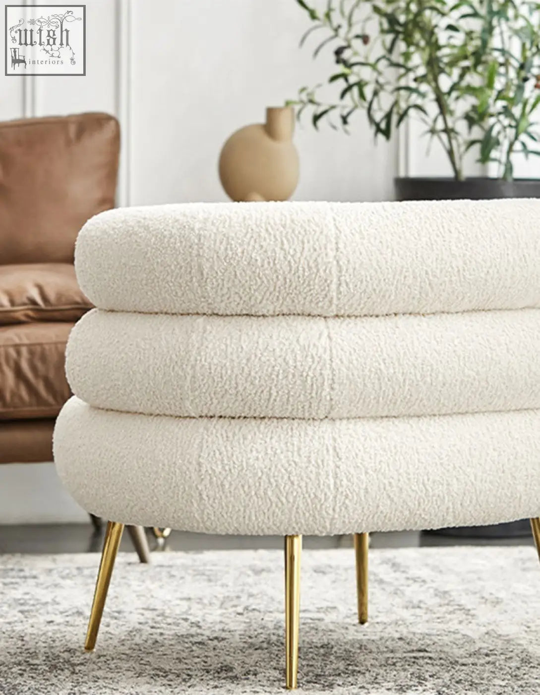 Cream-colored plush sheepskin-textured ottoman with slender gold legs that adds art-deco glamour to demure boucle interiors