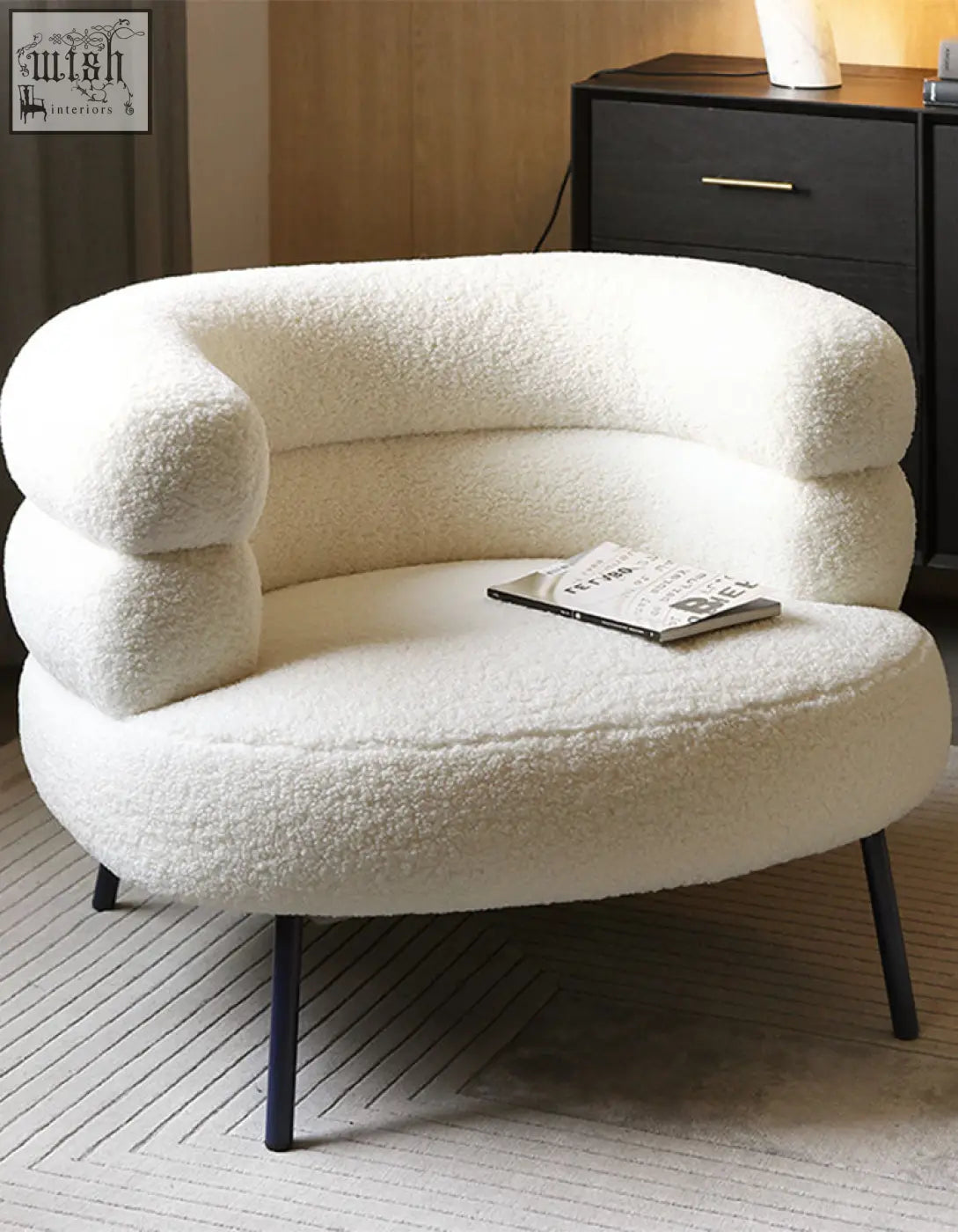 Demure boucle armchair with cream-colored plush sheepskin texture and sleek black metal legs adds art-deco glamour