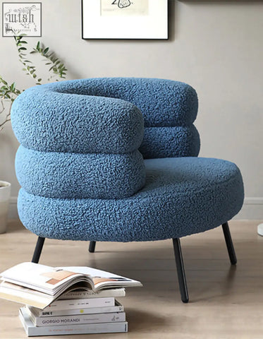 Demure boucle armchair in light blue sheepskin texture with rounded cushions and slim black legs adds art deco glamour